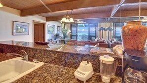 A kitchen with granite countertops, a coffee maker, and a blender.
