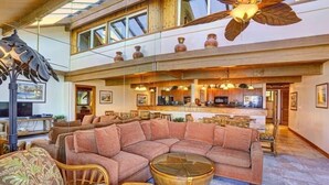 A spacious living area with a large sectional sofa, a round coffee table, and a ceiling fan.