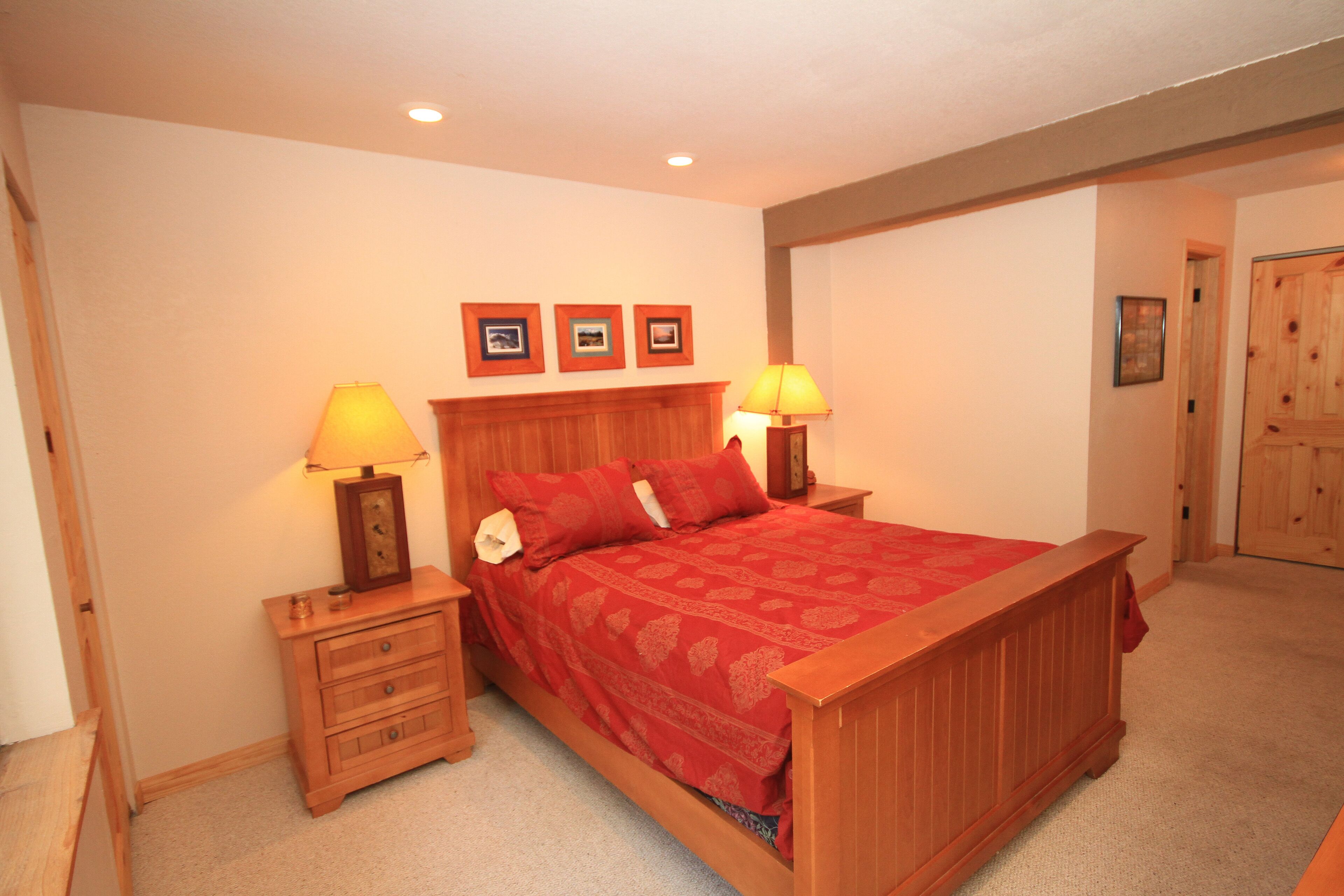A bedroom with a wooden bed, two nightstands with lamps, a dresser, and three framed pictures on the wall.