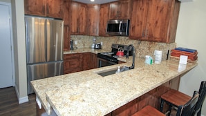 A kitchen with wooden cabinets, stainless steel appliances, granite countertops, and a built-in sink. - Mammoth Ski & Racquet Club #12 - Pet Friendly (Mammoth Lakes)
