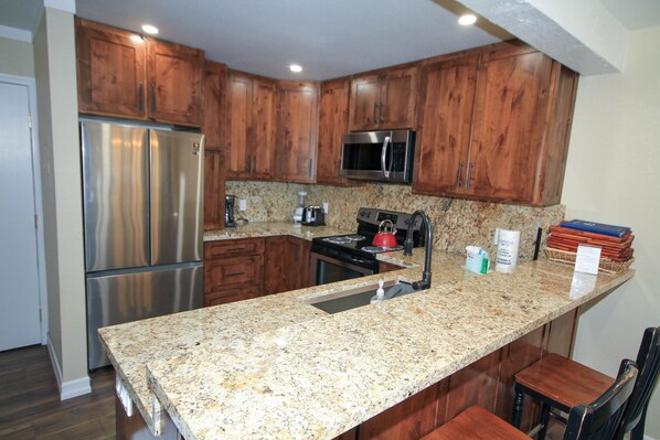 A kitchen with wooden cabinets, stainless steel appliances, granite countertops, and a built-in sink.