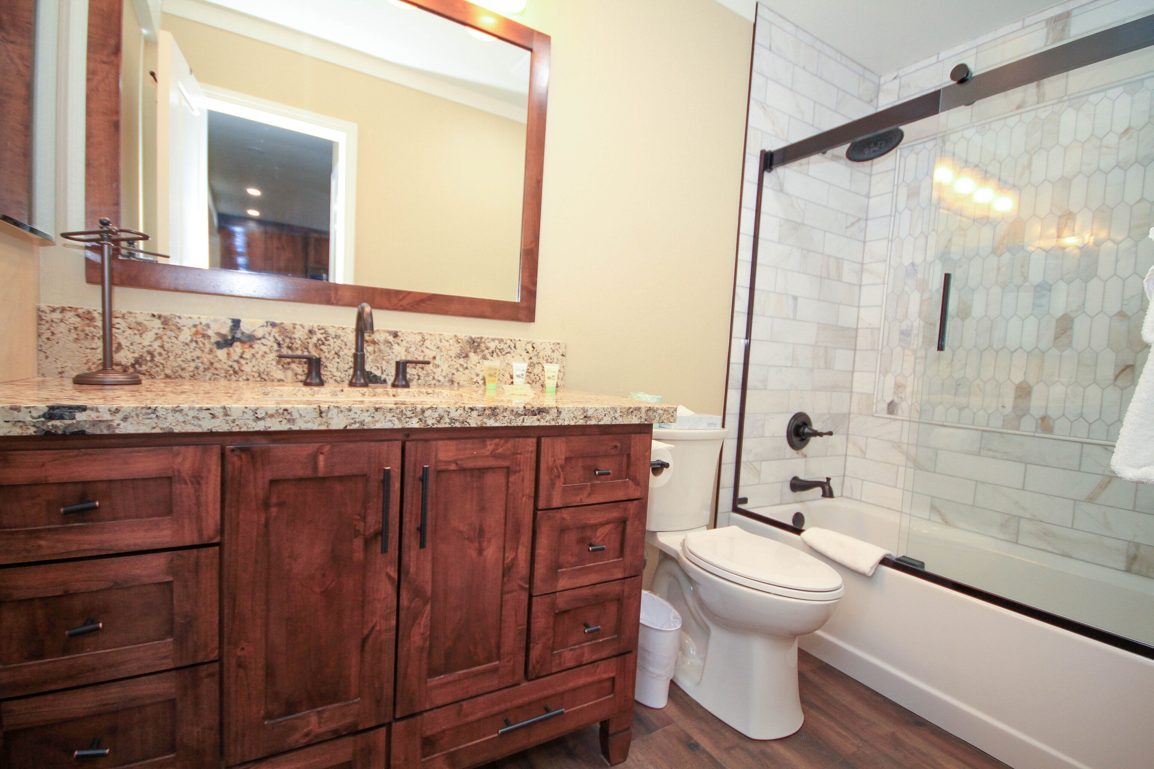 Une salle de bain avec un meuble-lavabo en bois, des toilettes et une douche à parois de verre.