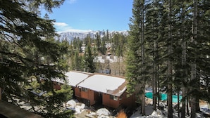 A cabin with a snow-covered roof, surrounded by tall evergreen trees and a mountain backdrop. - Mammoth Ski & Racquet Club #12 - Pet Friendly (Mammoth Lakes)