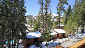 A snow-covered mountain with a clear sky, a wooden deck, and a building with a snow-covered roof. - Mammoth Ski & Racquet Club #12 - Pet Friendly (Mammoth Lakes)