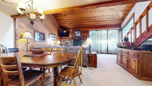 A cozy cabin interior with a dining area, sofa, and fireplace. - Spacious Home, Private Laundry. Near Shops & Restaurants, Pool On-site (Mammoth Lakes)