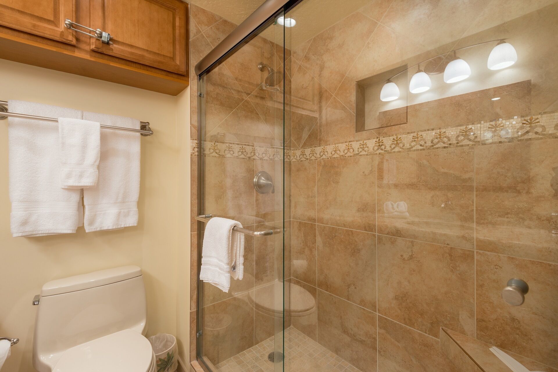 Une salle de bain avec une douche à parois de verre, des toilettes et un porte-serviettes avec des serviettes.