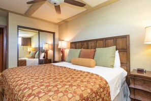 A hotel room with a large bed, a wooden headboard, two bedside lamps, and a ceiling fan. - Direct Oceanfront • AC • Top Floor Views • Peaceful West Maui (Kahana)
