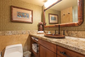 A bathroom with a wooden vanity, a sink with a wooden basin, a framed picture on the wall, and a toilet. - Direct Oceanfront • AC • Top Floor Views • Peaceful West Maui (Kahana)