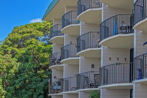 A multi-story building with balconies, each featuring a small table and chairs. - Direct Oceanfront • AC • Top Floor Views • Peaceful West Maui (Kahana)