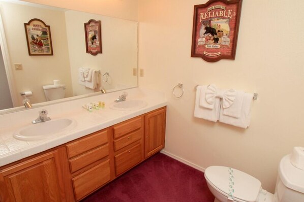 Une salle de bain avec un double lavabo, des meubles en bois, des toilettes et un miroir.