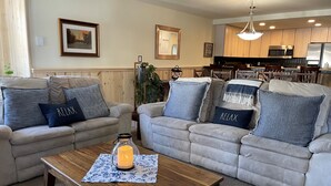 A living room with two sofas, a coffee table, and a kitchen in the background. - Mountainback #57, Den (Mammoth Lakes)