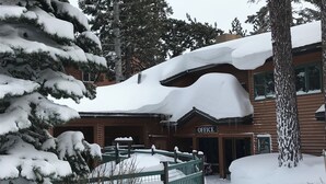 A wooden lodge with a sign reading "OFFICE" at the entrance, surrounded by snow-covered trees and a fenced area. - Mountainback #57, Den (Mammoth Lakes)