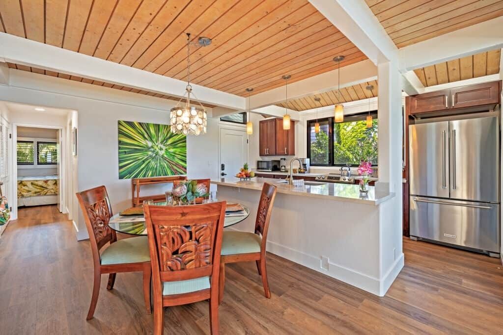 A modern kitchen with a central island, wooden dining table, and chairs.