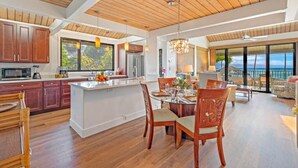 Una cocina amplia con armarios de madera, una isla grande y una zona de comedor con vistas al océano.