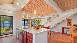 Una cocina amplia con una isla grande, piso de madera y vista al océano.