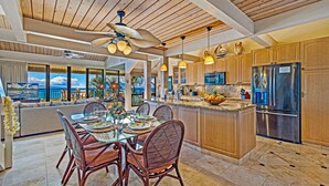 A spacious kitchen with a large island, wooden cabinets, and a view of the ocean. - Kahana Village #21 Beach Front Luxury (Lahaina)