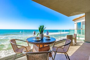A round table with chairs on a balcony overlooking the ocean. - Single Family Gorgeous Beachfront Mansion on the Sand P1733-0 (Oceanside)