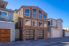 A two-story house with a stone facade, multiple windows, and a garage. - Single Family Gorgeous Beachfront Mansion on the Sand P1733-0 (Oceanside)
