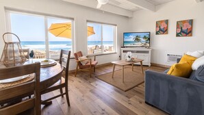 A living room with a view of the ocean, a ceiling fan, a TV, and a sofa with yellow cushions. - Oceanfront Getaway with Private Sandy Beach - 1615-1 (Oceanside)