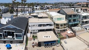 A residential complex with multiple units, including a lower level unit with a rooftop patio and a second floor unit with a balcony. - Oceanfront Getaway with Private Sandy Beach - 1615-1 (Oceanside)