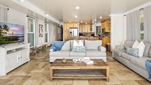 A spacious living room with a large flat-screen TV, two sofas, a coffee table, and a kitchen in the background. - Single Family Beautiful Home with Two Spas P815-X (Oceanside)