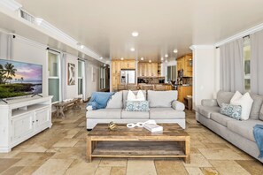 A spacious living room with a large flat-screen TV, two sofas, a coffee table, and a kitchen in the background. - Single Family Beautiful Home with Two Spas P815-X (Oceanside)