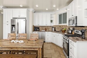 A modern kitchen with white cabinetry, a wooden dining table, and a stone backsplash. - Single Family Beautiful Home with Two Spas P815-X (Oceanside)