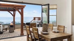 A dining area with a view of the ocean, a grill, and a fire pit. - Luxurious Single Family Pet Friendly Oceanfront Home with Two Spas P825-X (Oceanside)