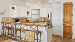 A kitchen with white cabinetry, a wooden door, and a bar area with stools. - Luxurious Single Family Pet Friendly Oceanfront Home with Two Spas P825-X (Oceanside)