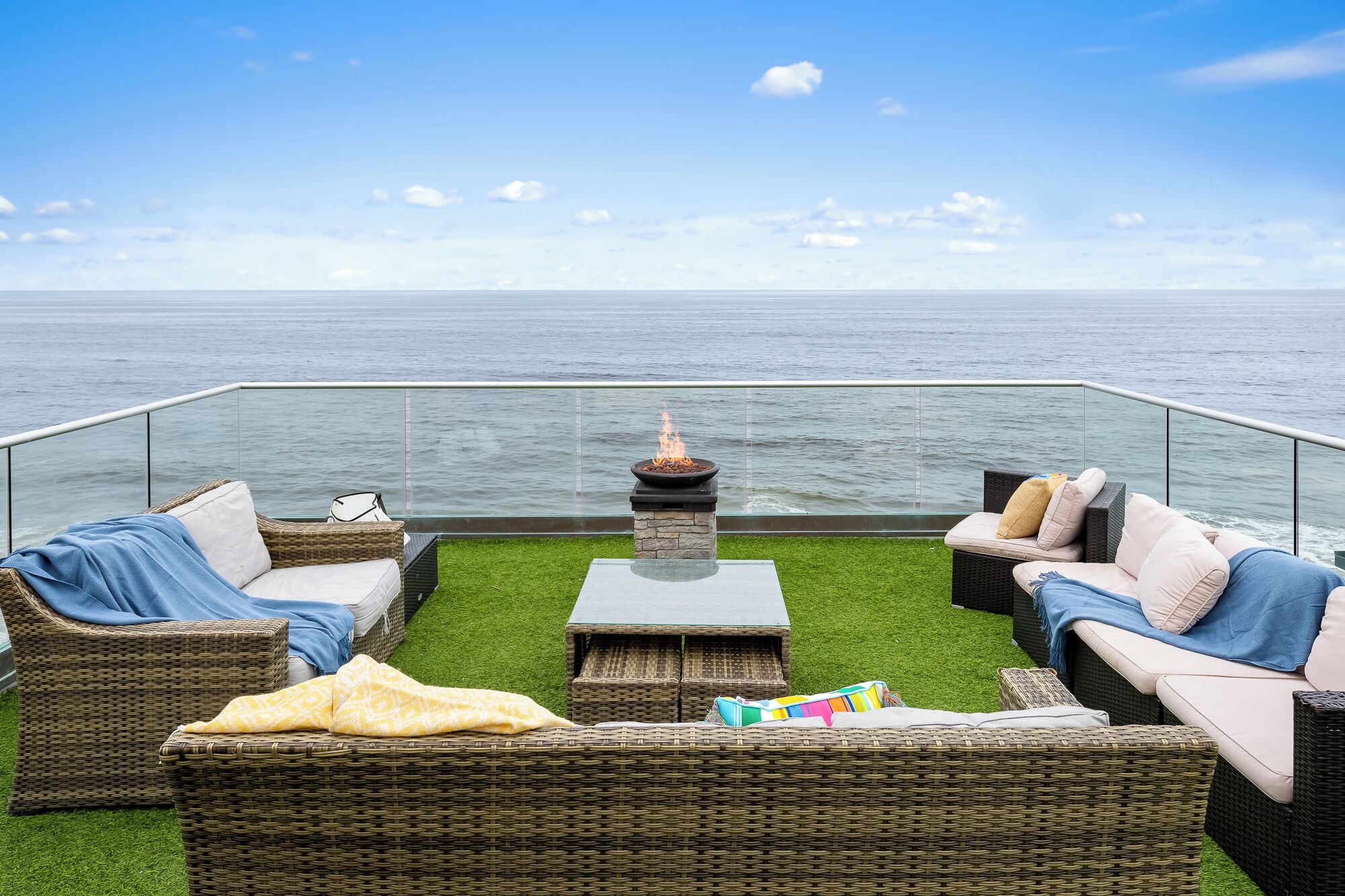 A balcony with wicker furniture, a fire pit, and a view of the sea.