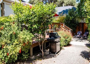 A backyard with a barbecue grill, wooden deck, and outdoor seating.