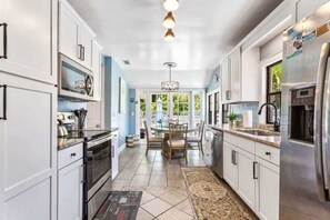 A modern kitchen with white cabinets, stainless steel appliances, and a dining area with a table and chairs.