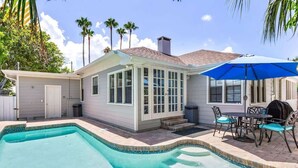 A pool area with a house, patio furniture, and palm trees. - Coconut Beach House: 4BR Pool Home in Clearwater (Clearwater Beach)