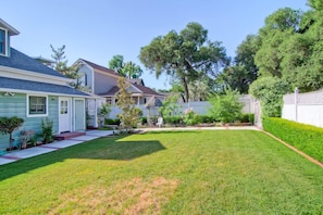 A residential area with a well-maintained lawn, a small garden, and a white picket fence.