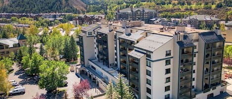 A multi-story hotel with a central courtyard, surrounded by trees and a mountainous backdrop.