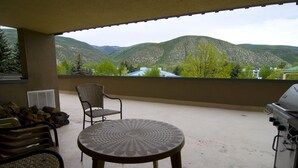 Un balcón con mesa y sillas, una parrilla y vistas a las montañas.
