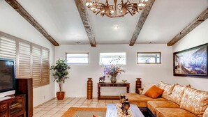 A living room with a television, sofa, coffee table, and decorative items. - Vineyard Views + Jetted Tub | Paso Robles Wine Country | Solitude I (Paso Robles)