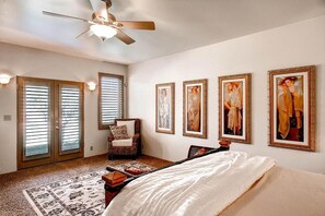 A bedroom with a bed, a chair, a ceiling fan, and four framed pictures on the wall. - Vineyard Views + Jetted Tub | Paso Robles Wine Country | Solitude I (Paso Robles)