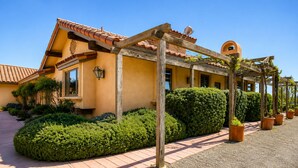 A building with a tiled roof, a wooden pergola, and well-maintained hedges. - Vineyard Views + Jetted Tub | Paso Robles Wine Country | Solitude I (Paso Robles)