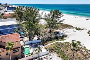 A beachside property with a pool, a view of the beach, and a clear sky.