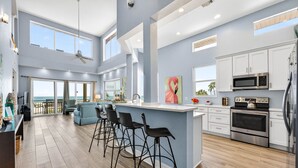 A spacious kitchen with a large island, bar stools, and modern appliances. - Treasure Island Villa, Beachfront, Private Pool! (Treasure Island)