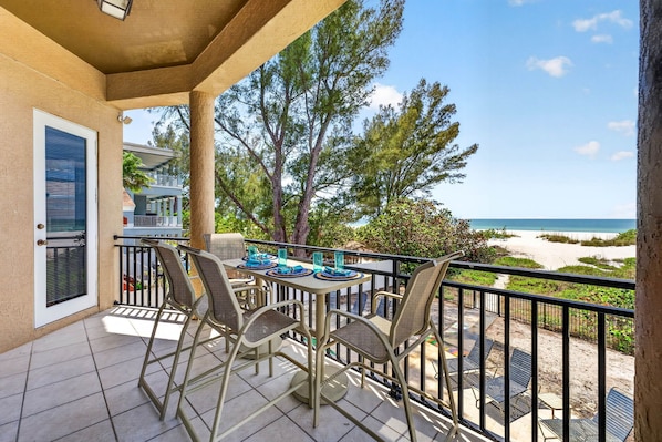 A balcony with outdoor furniture, a view of the beach, and a door with a window.