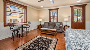 A room with a wooden floor, a ceiling fan, a sofa, a small table, a chair, a bed, and two windows. - 2 Ensuite Suites + Walk to Downtown | Paso Robles | Lewis Loft (Paso Robles)