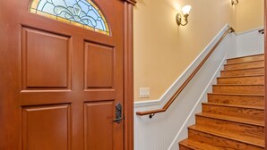 A wooden door with a stained glass window, a white wainscoting, and a wooden staircase with a white railing. - 2 Ensuite Suites + Walk to Downtown | Paso Robles | Lewis Loft (Paso Robles)