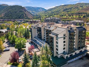 A multi-story hotel with a central courtyard, surrounded by trees and a mountainous backdrop.