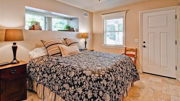 A bedroom with a bed, bedside lamps, a window, and a door. - Spa + Chef's Kitchen | Downtown Paso Robles | Downtown Diggs (Paso Robles)
