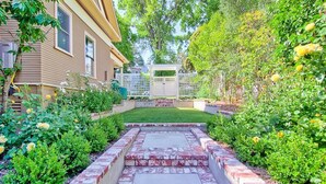 A residential backyard with a paved patio, a lawn, and various plants and flowers. - Spa + Chef's Kitchen | Downtown Paso Robles | Downtown Diggs (Paso Robles)