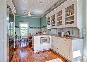 A kitchen with white cabinetry, a central island, and a dining area with chairs.