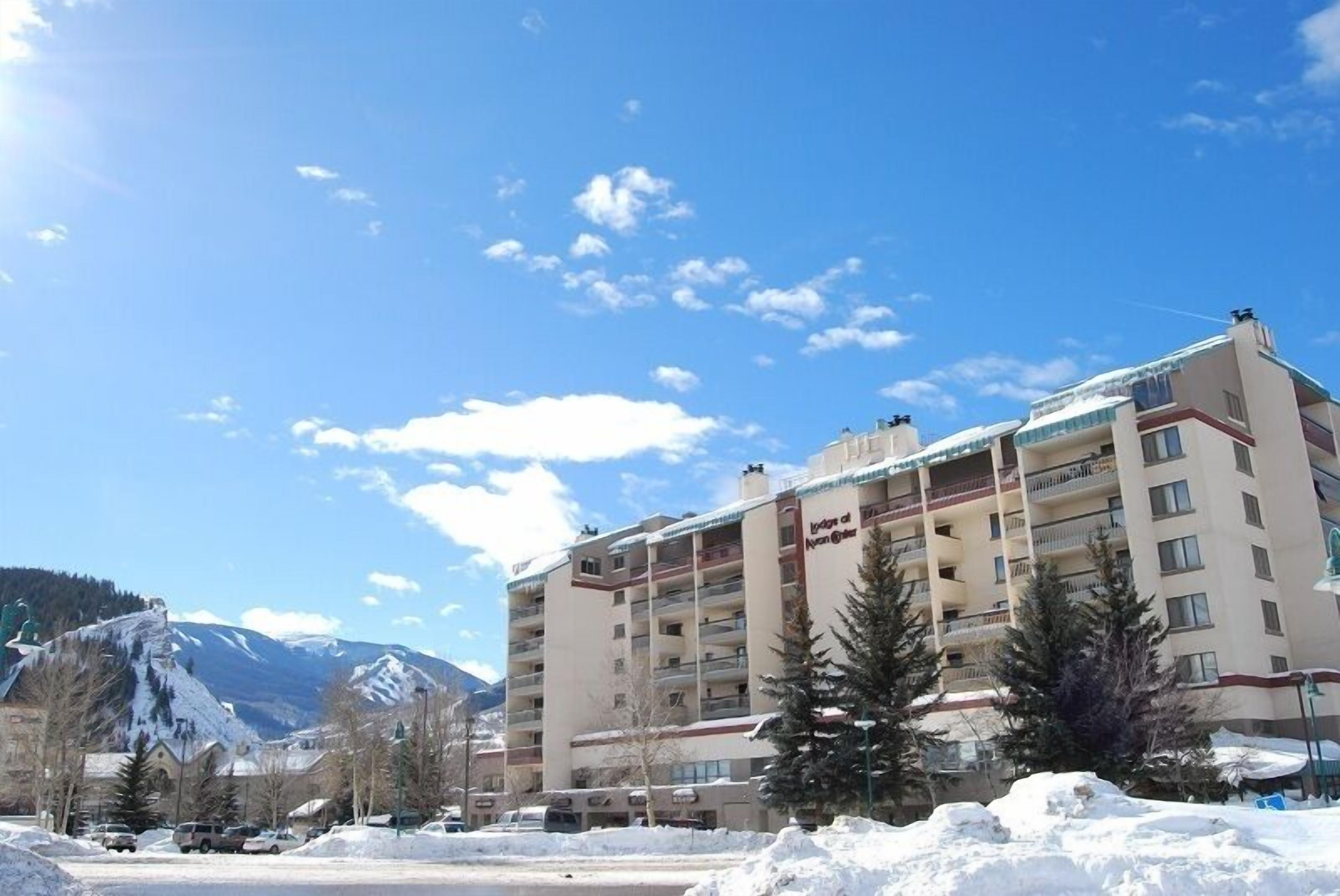 Ein mehrstöckiges Hotel mit Balkonen in einer verschneiten Gegend mit Bergen im Hintergrund.