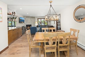 A dining area with a wooden table and chairs, a stone fireplace, and a television mounted on the wall.